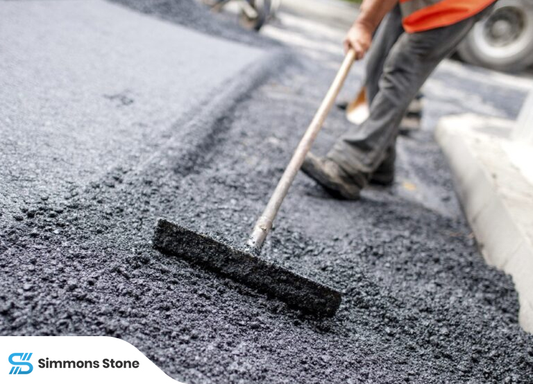 Close-up of workers applying hot mix asphalt to the surface.